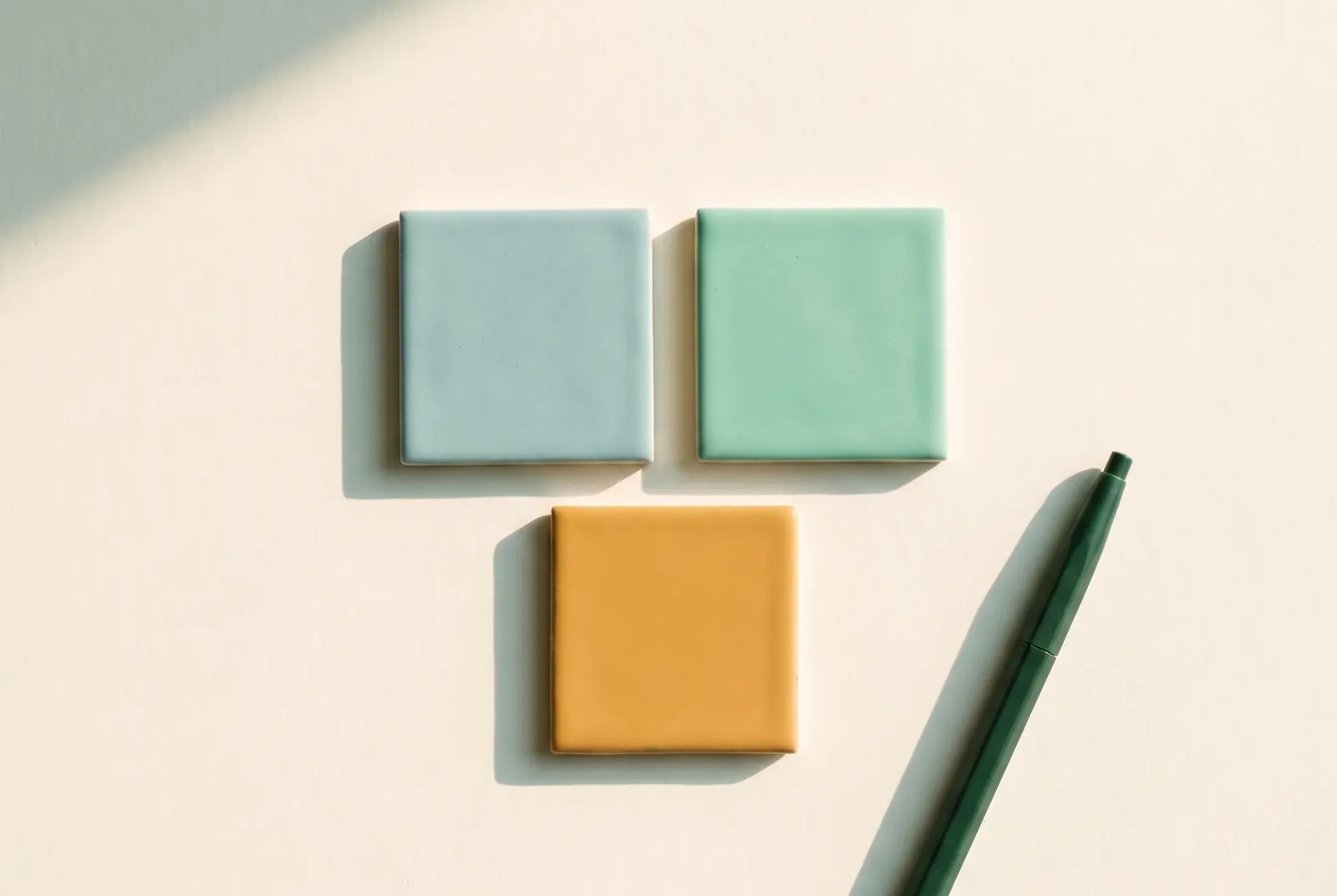 Two green tiles side by side with one orange tile below them and a pen